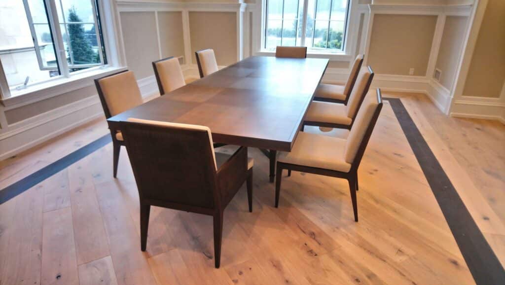 Completely restored Baker dining table with matching upholstered dining chairs, showcasing refinished wood surfaces and updated premium upholstery.
